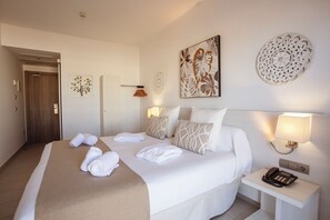 Quarto de hotel com cama bem arrumada, abajur, telefone e arte decorativa na parede.