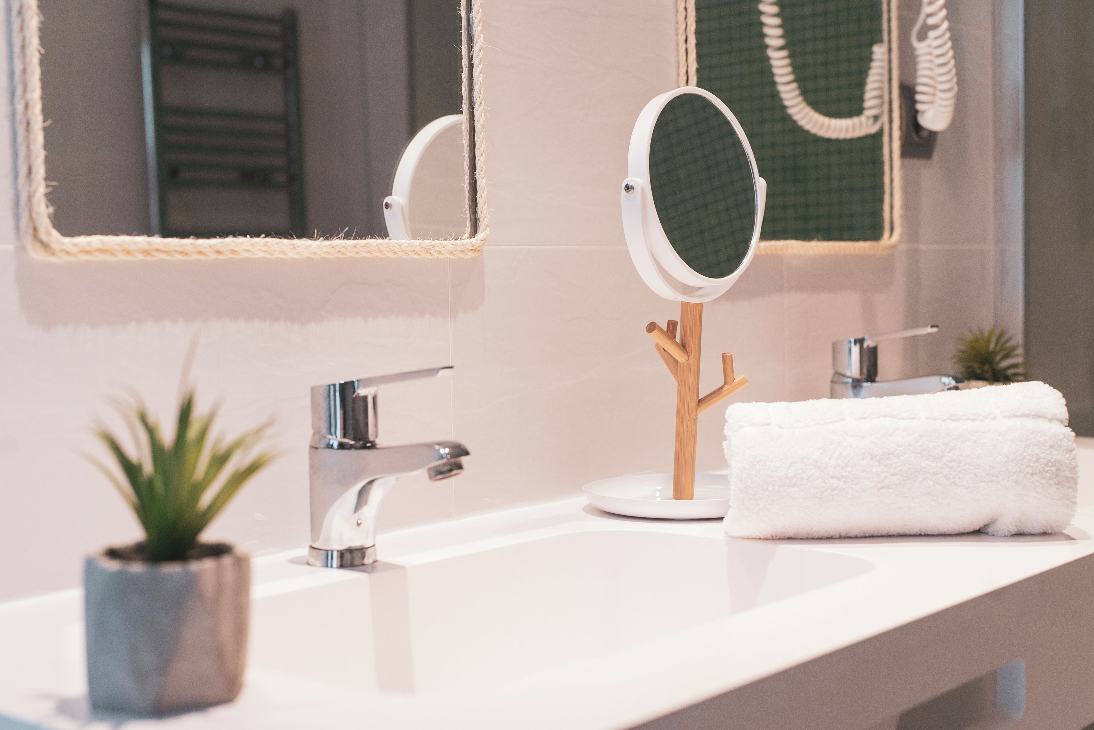 A bathroom with a white sink, a mirror, a towel, and a small potted plant.