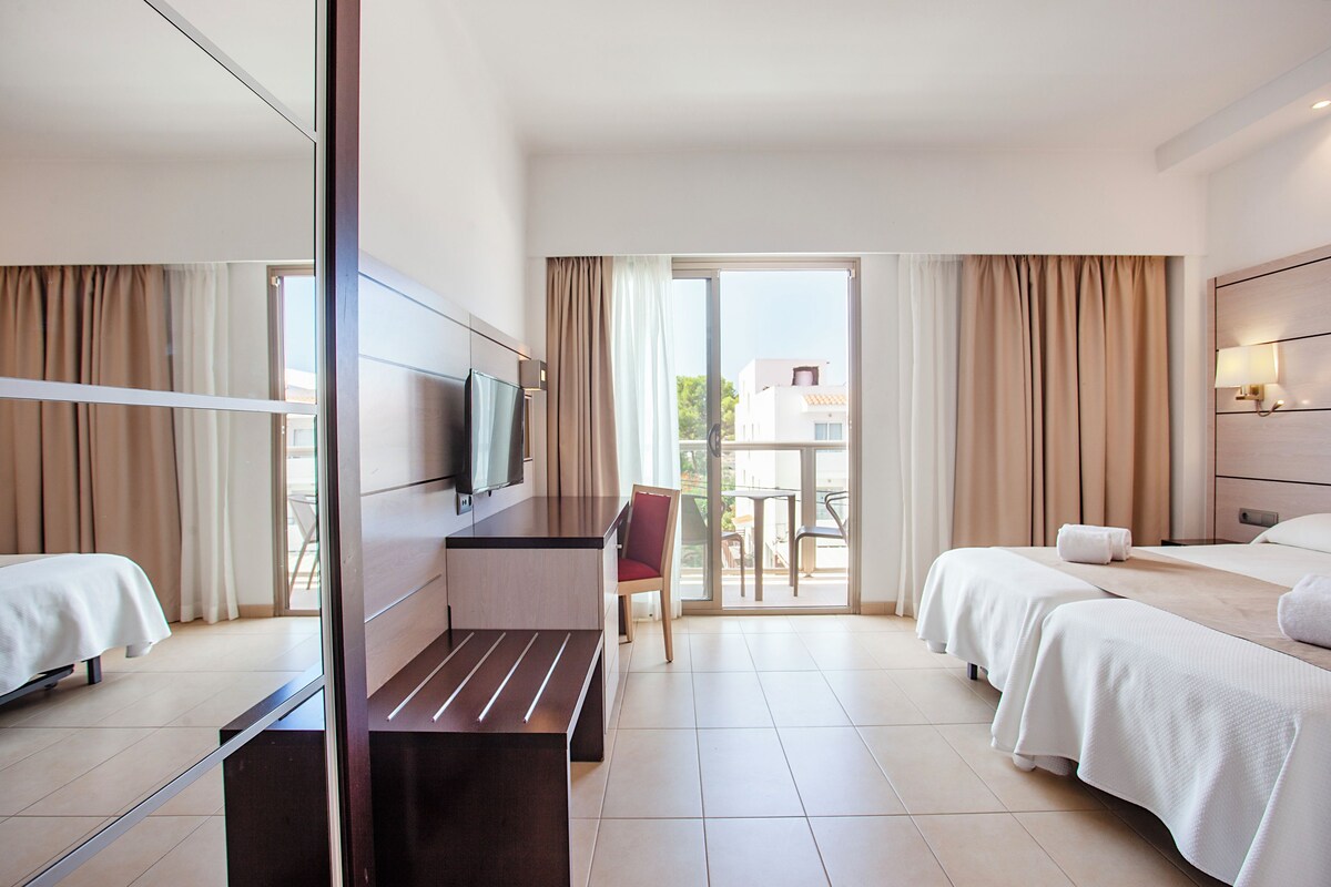 Ein Hotelzimmer mit zwei Betten, einem Fernseher, einem Schreibtisch und einem Stuhl.