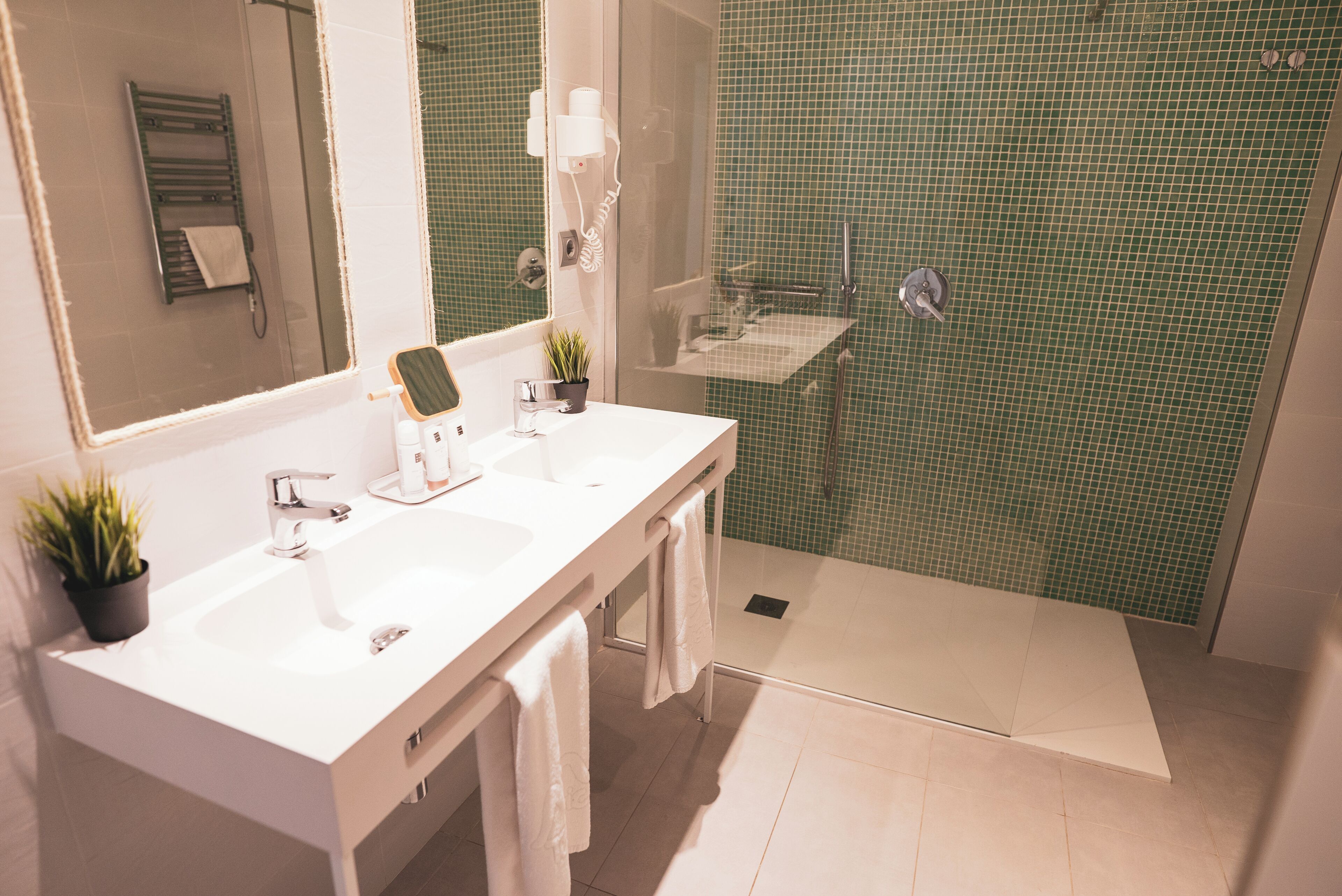 A modern bathroom with two sinks, a large mirror, and a shower area.