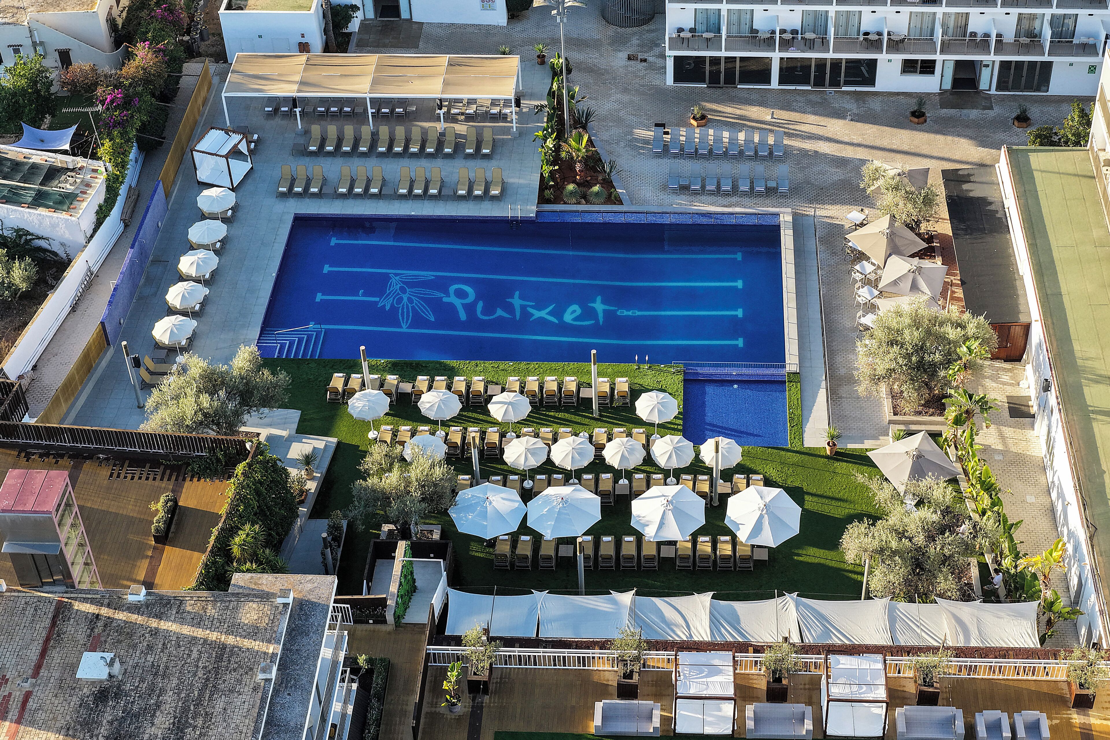 Vista aérea de un hotel con piscina, tumbonas, sombrillas y un bar en la azotea.
