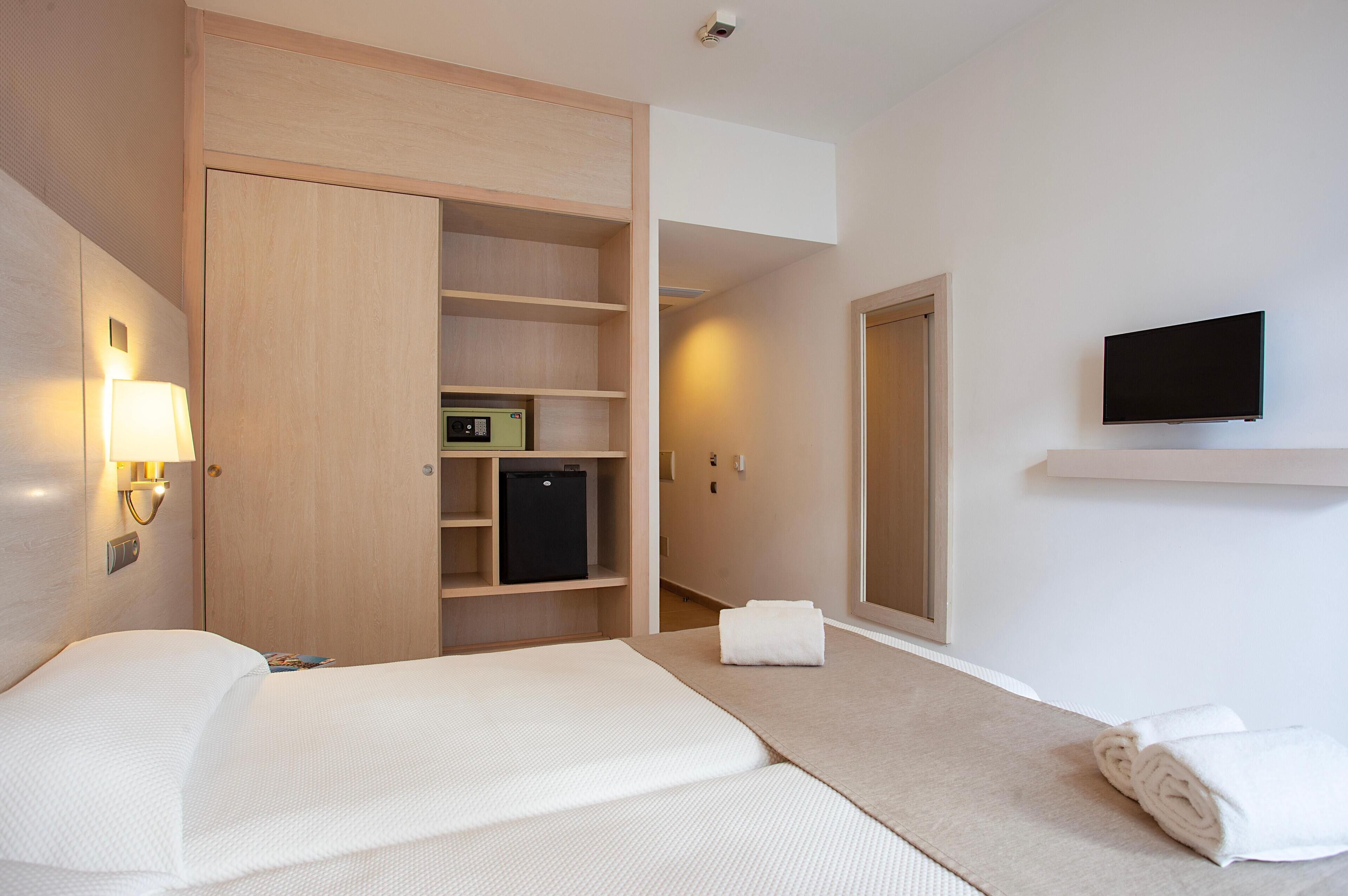 A hotel room with a bed, a wardrobe, a television, and a bathroom.