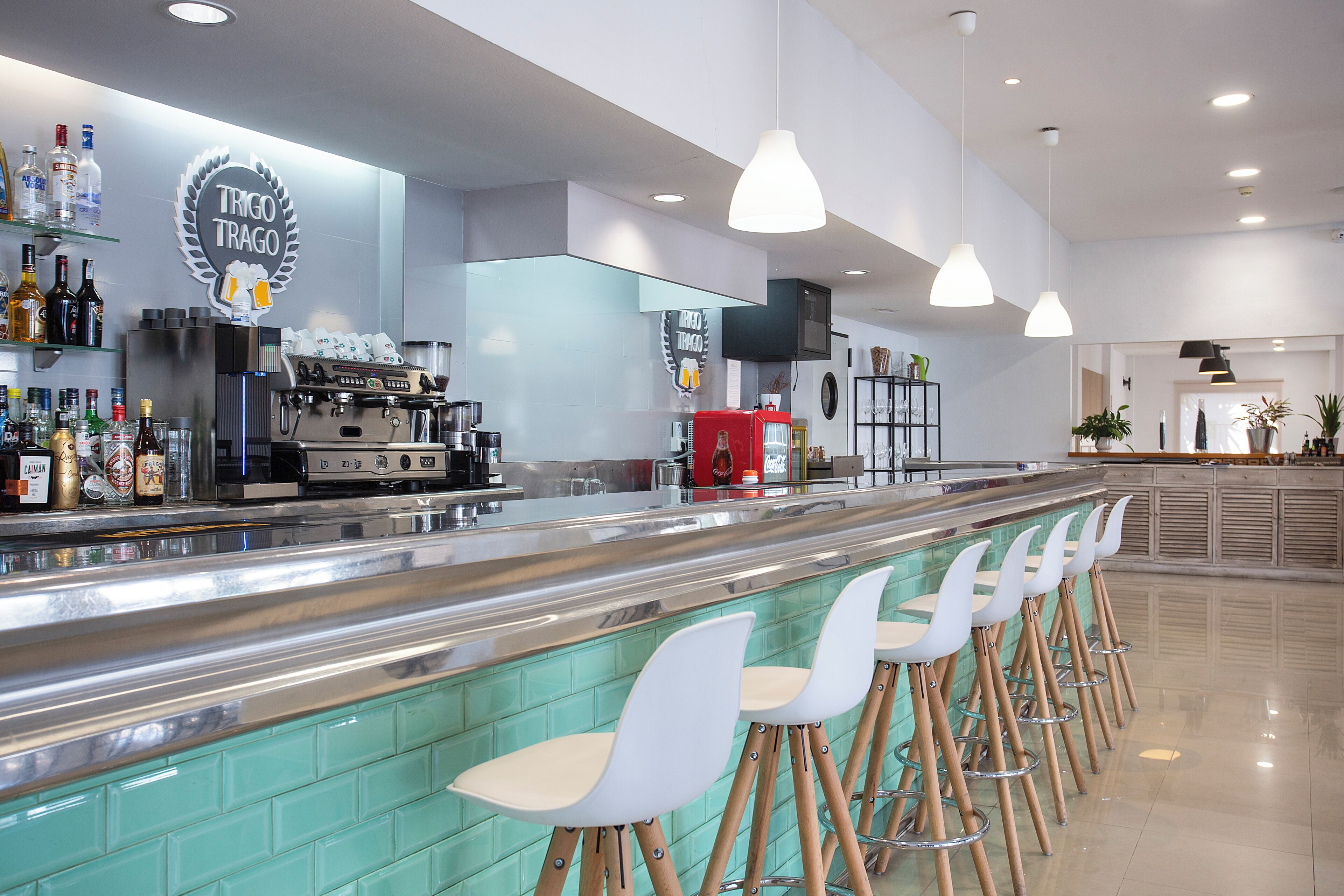 Een bar met een toonbank, krukken en een koffiemachine.