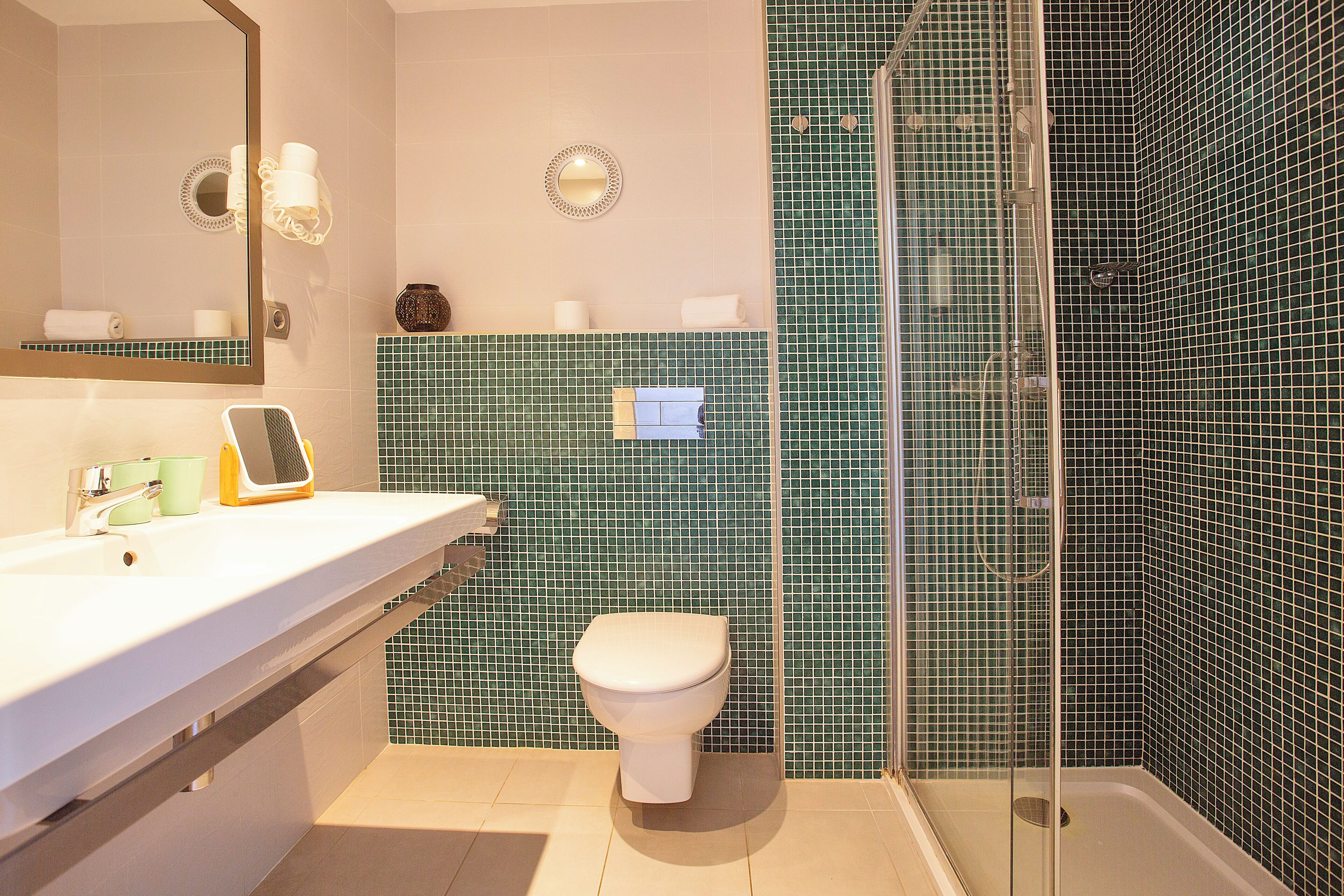 A bathroom with a white sink, a toilet, and a shower area with glass doors.