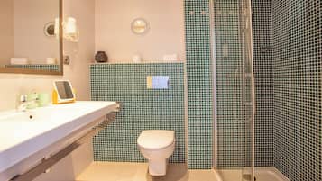 Une salle de bain avec un lavabo blanc, des toilettes et un espace douche doté de portes en verre.