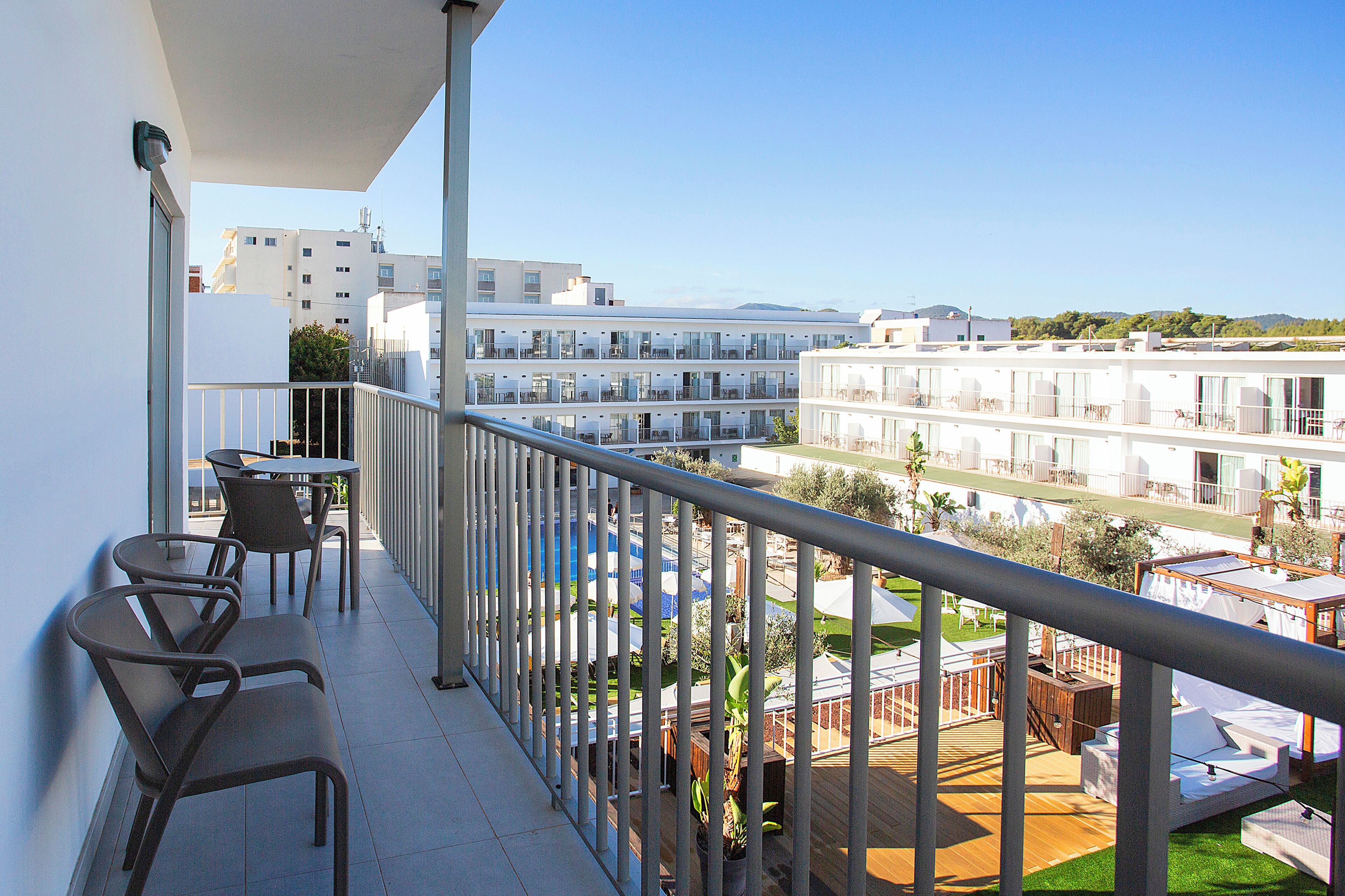 Un balcón con vistas a un moderno complejo de edificios, mobiliario exterior y una zona de terraza de madera.