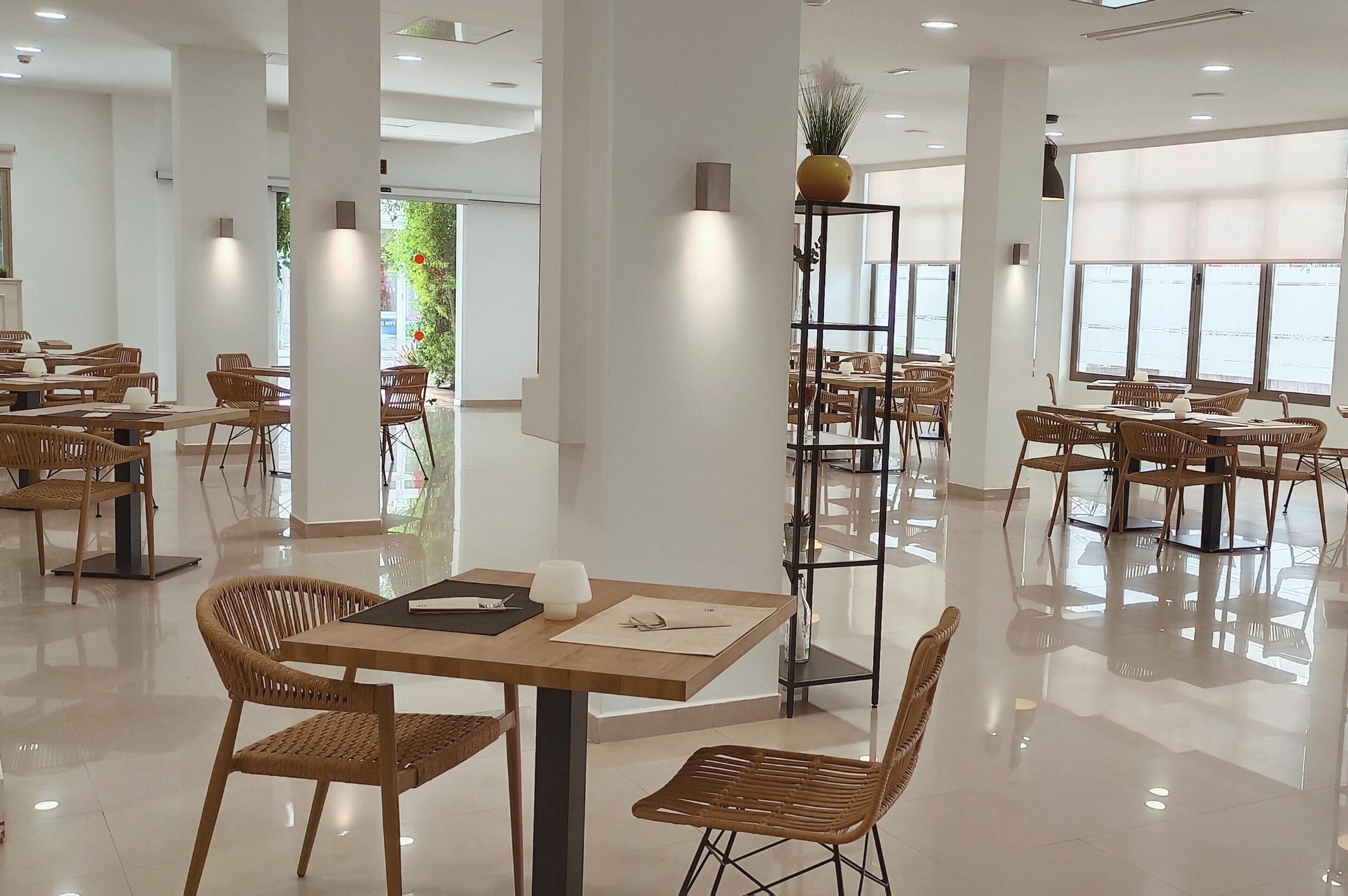 Un restaurant moderne avec des tables et des chaises en bois, de grandes fenêtres et un sol propre et bien entretenu.