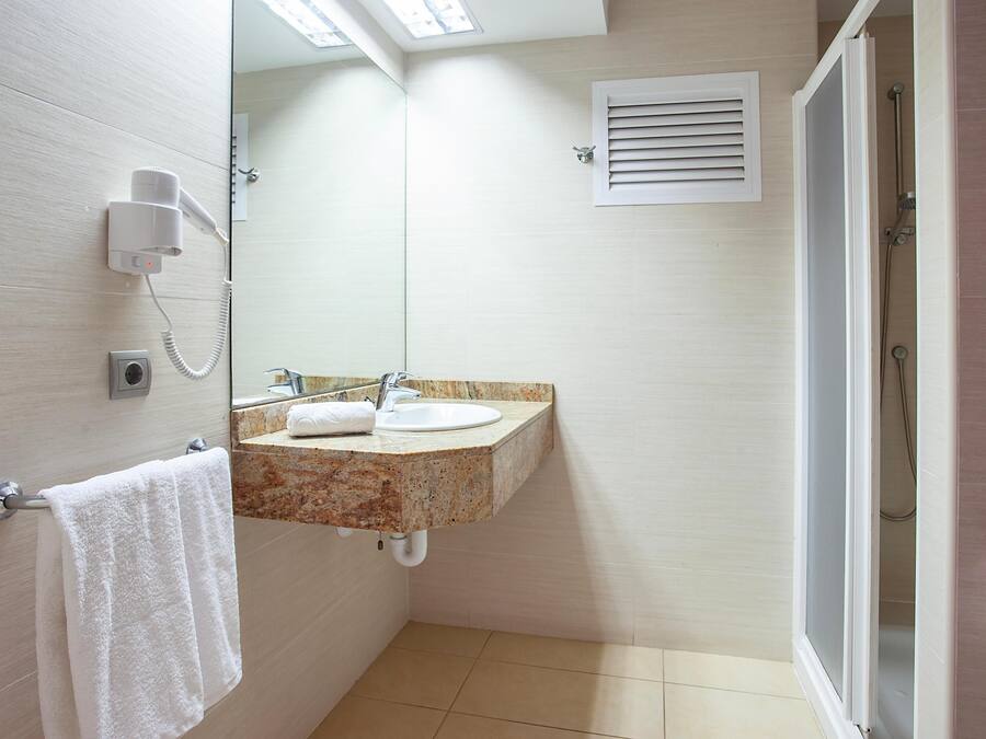 A bathroom with a sink, mirror, towel rack, and a shower area.