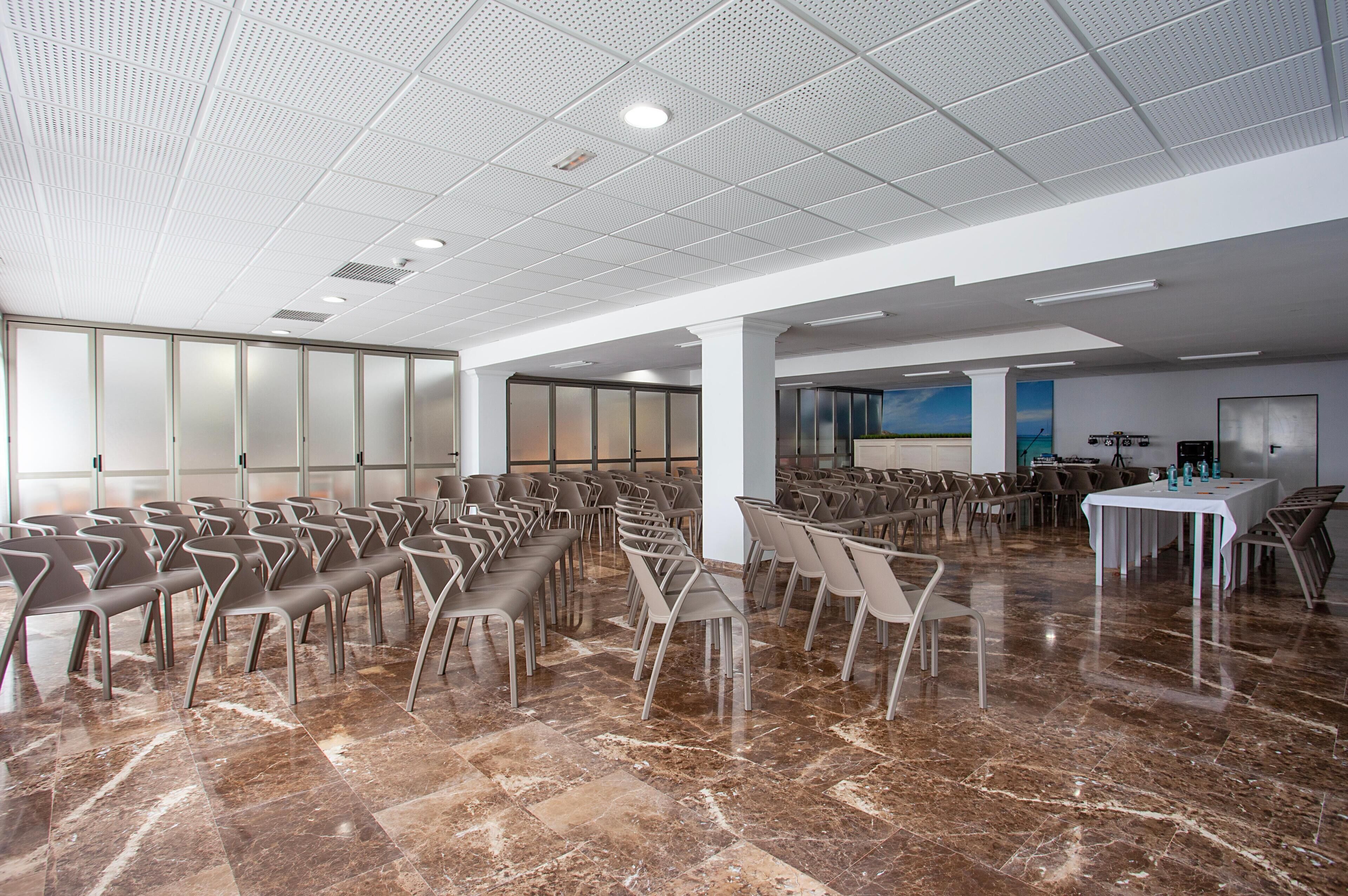 A spacious conference room with rows of chairs, a marble floor, and a large screen for presentations.