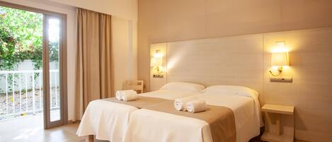 A hotel room with a large bed, two bedside tables, and a sliding glass door leading to a balcony.