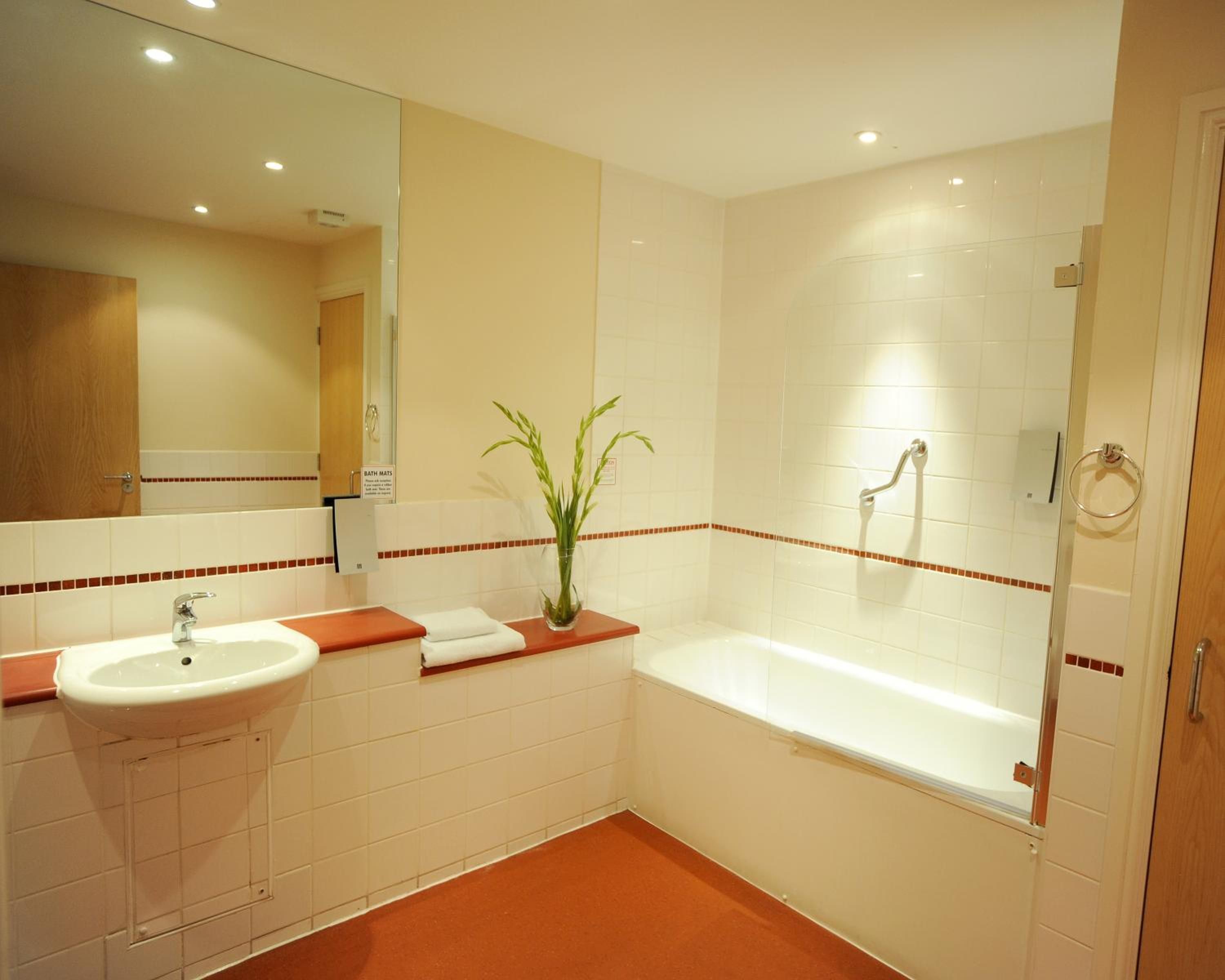 A bathroom with a sink, mirror, and bathtub.