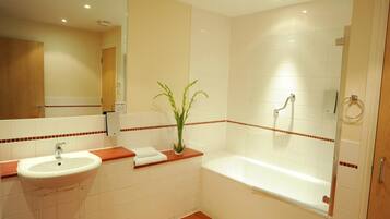 A bathroom with a sink, mirror, and bathtub.