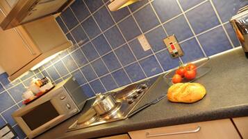 Una cocina con microondas, estufa y una hogaza de pan sobre la encimera.