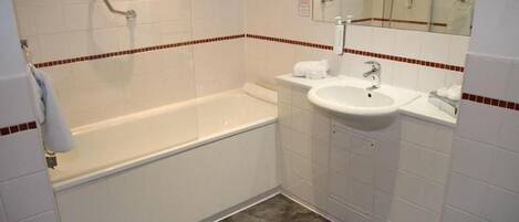 A bathroom with a bathtub, a sink, and a mirror.