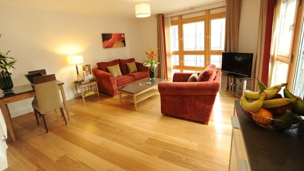 A living room with a sofa, coffee table, TV, and a fruit bowl. - PREMIER SUITES Bristol Redcliffe (Bristol)
