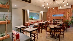 A restaurant with wooden walls, multiple tables and chairs, hanging light bulbs, and potted plants. - Hotel Miramar (San Juan)