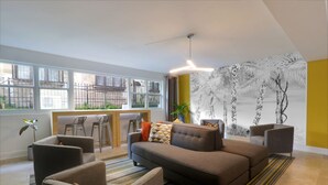 A modern living room with a sofa, armchairs, and a dining area with a table and chairs. - Hotel Miramar (San Juan)