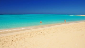 Una playa cerca, arena blanca, sillas reclinables de playa, sombrillas