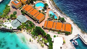 An aerial view of a resort with multiple buildings, a large central pool, and smaller pools.