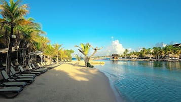 Ein Strandresort mit Liegestühlen, Palmen und ruhiger See.
