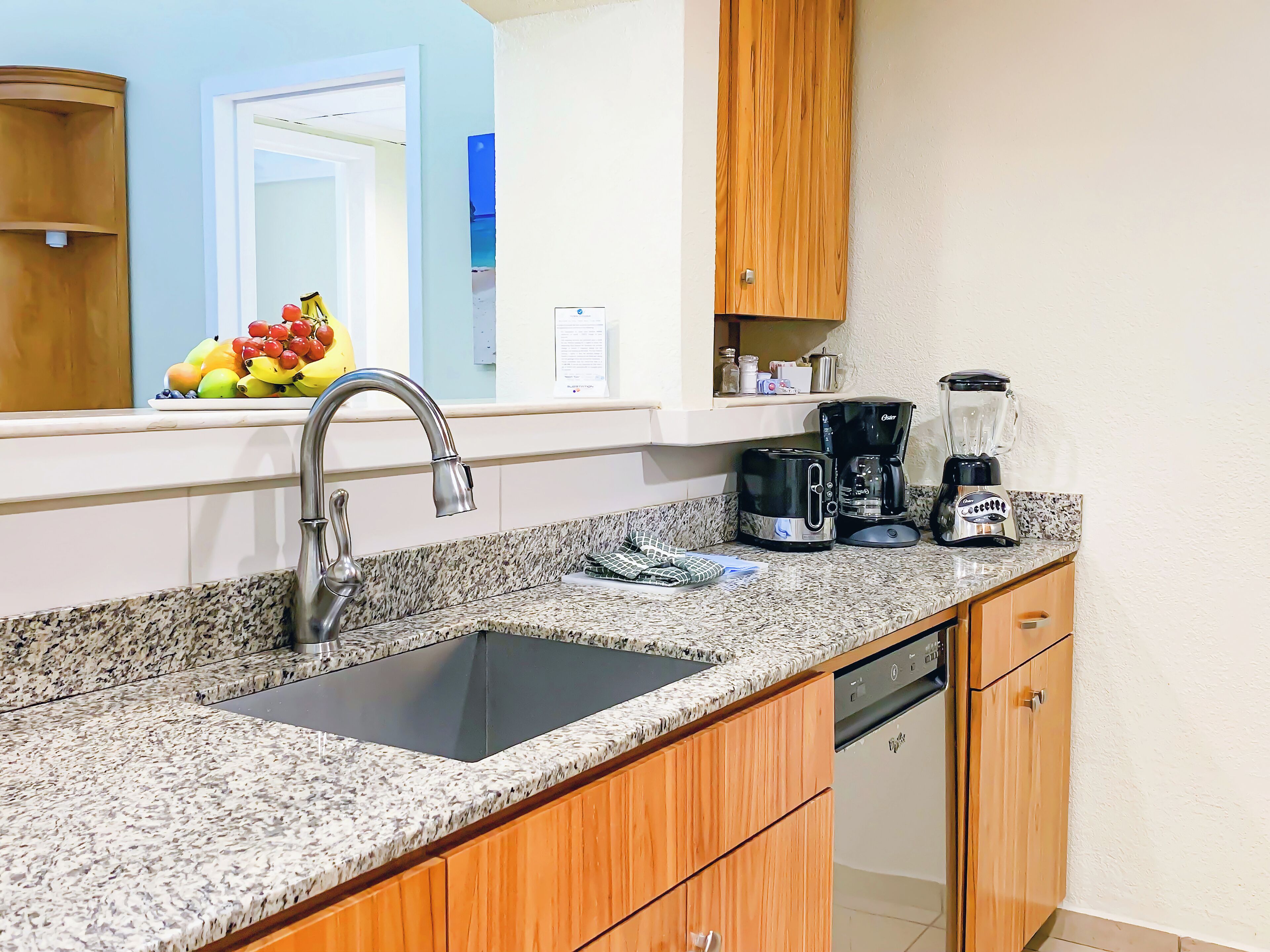 A kitchen with granite countertops, a stainless steel sink, a coffee maker, and a toaster.