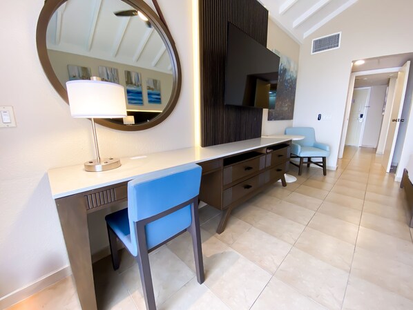 Una habitación de hotel moderna con escritorio, silla y un espejo grande.
