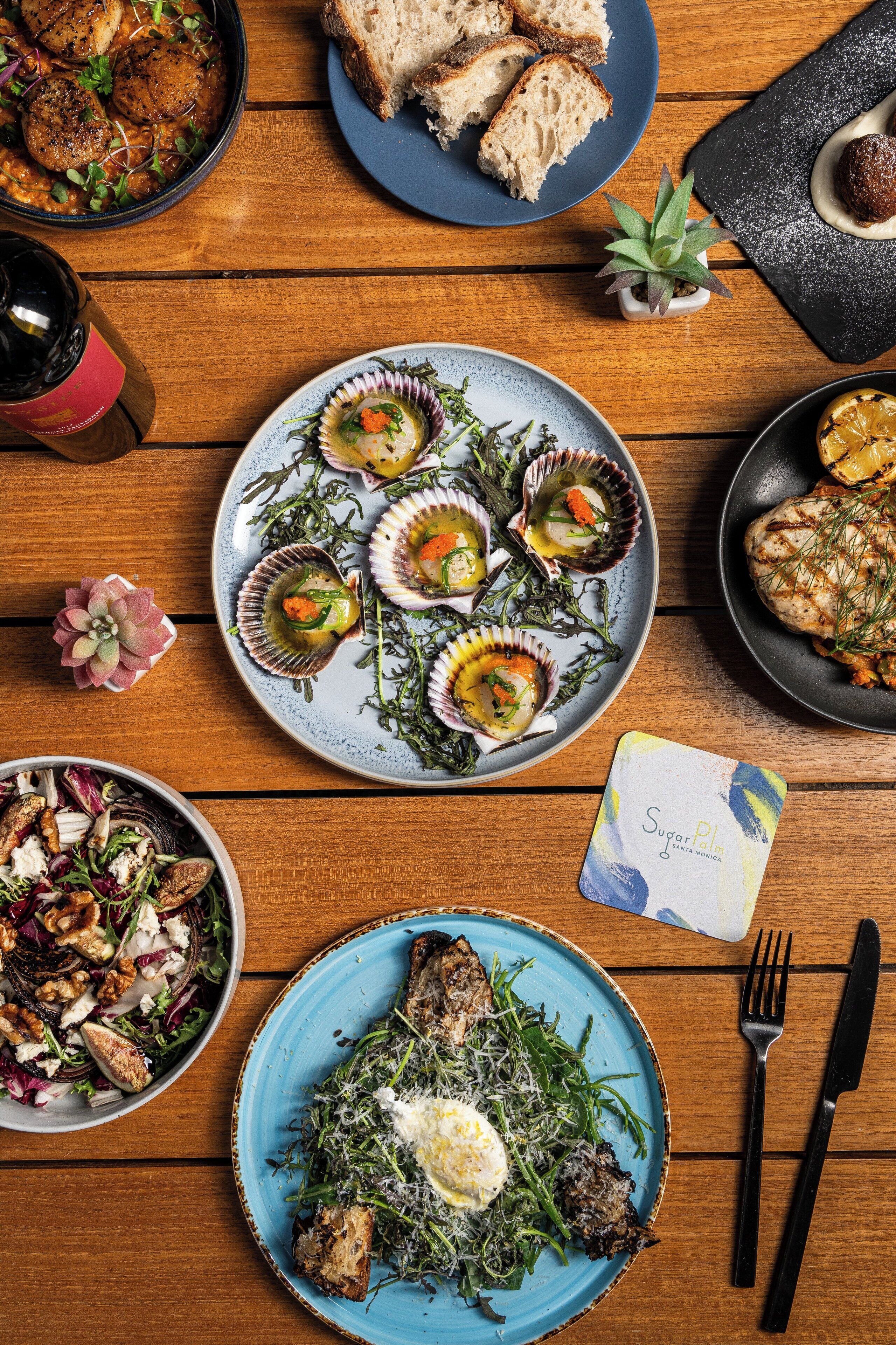 Una mesa de madera con diversos platos, como mariscos, pan y ensaladas.
