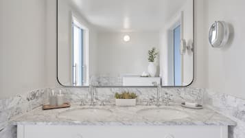 A bathroom with a large mirror, two sinks, and a white vanity.