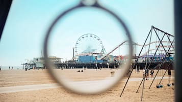 A beach with a Ferris wheel and amusement rides in the background.