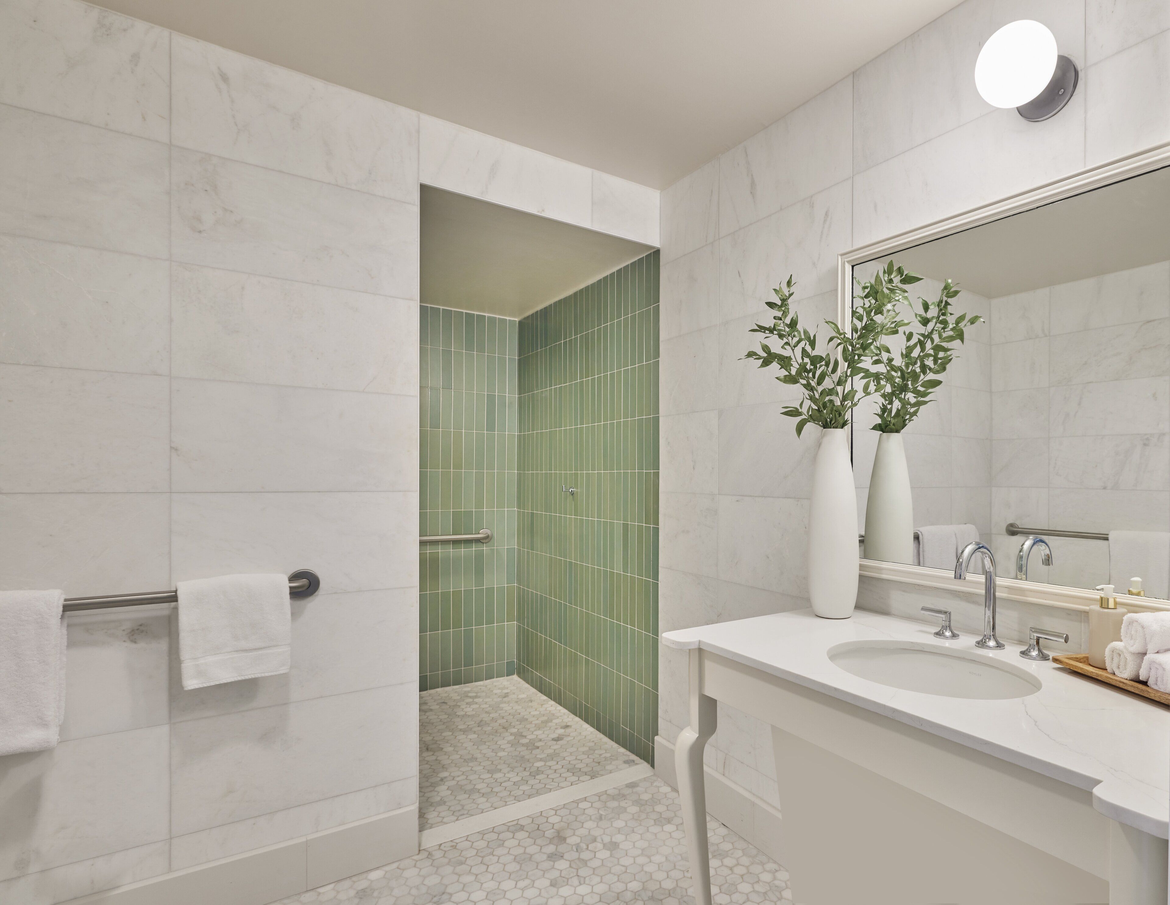 Een moderne badkamer met een douche, wastafel en spiegel.