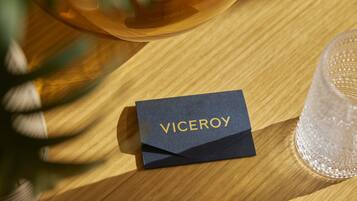 Una mesa de madera con una tarjeta azul oscuro que dice "VICEROY" y un vaso transparente.