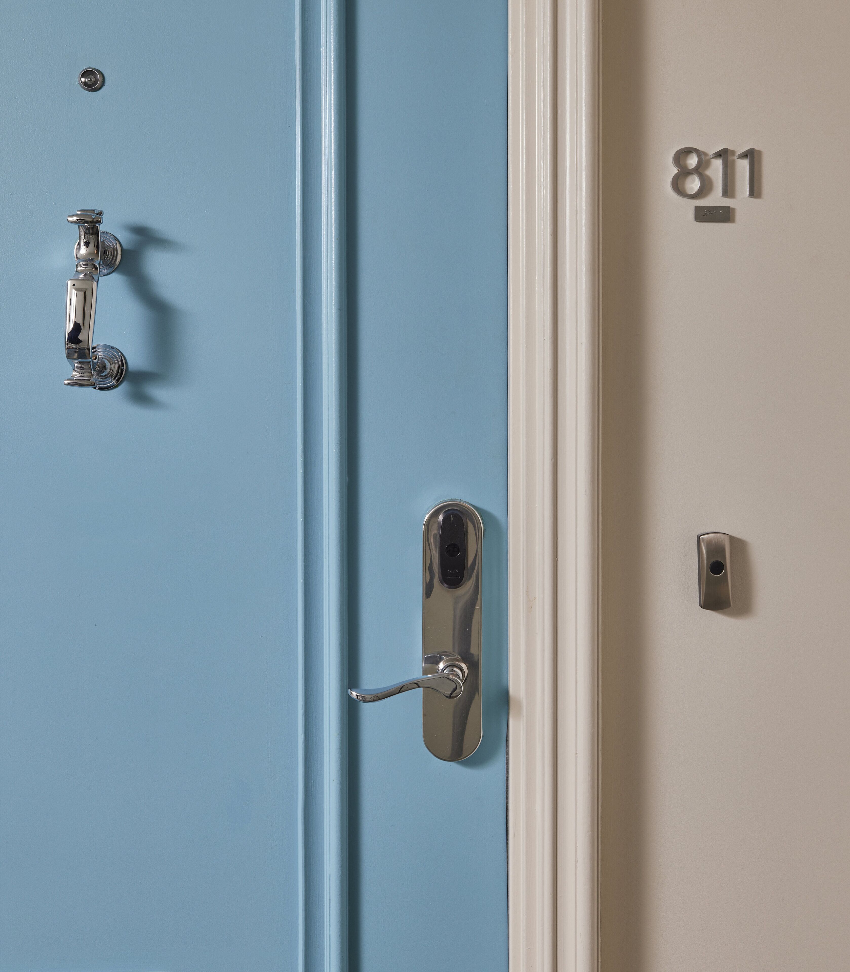 Eine blaue Tür mit silbernem Türgriff und einem Ziffernfeld.