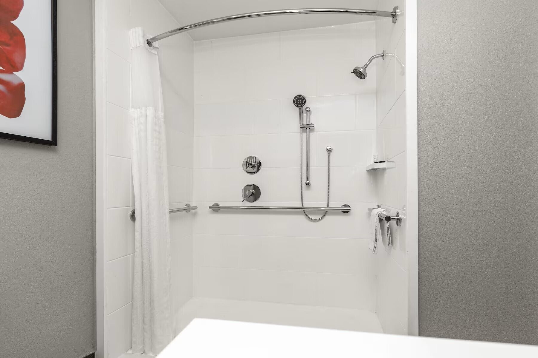 Eine weiße Duschkabine mit Handbrause und am Wand montiertem Wasserhahn.