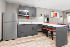 Una cocina moderna con armarios grises, microondas integrado y encimera blanca.