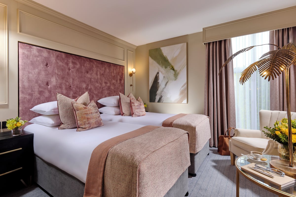 A hotel room with two beds, a sitting area, a coffee table, and a large window with curtains.