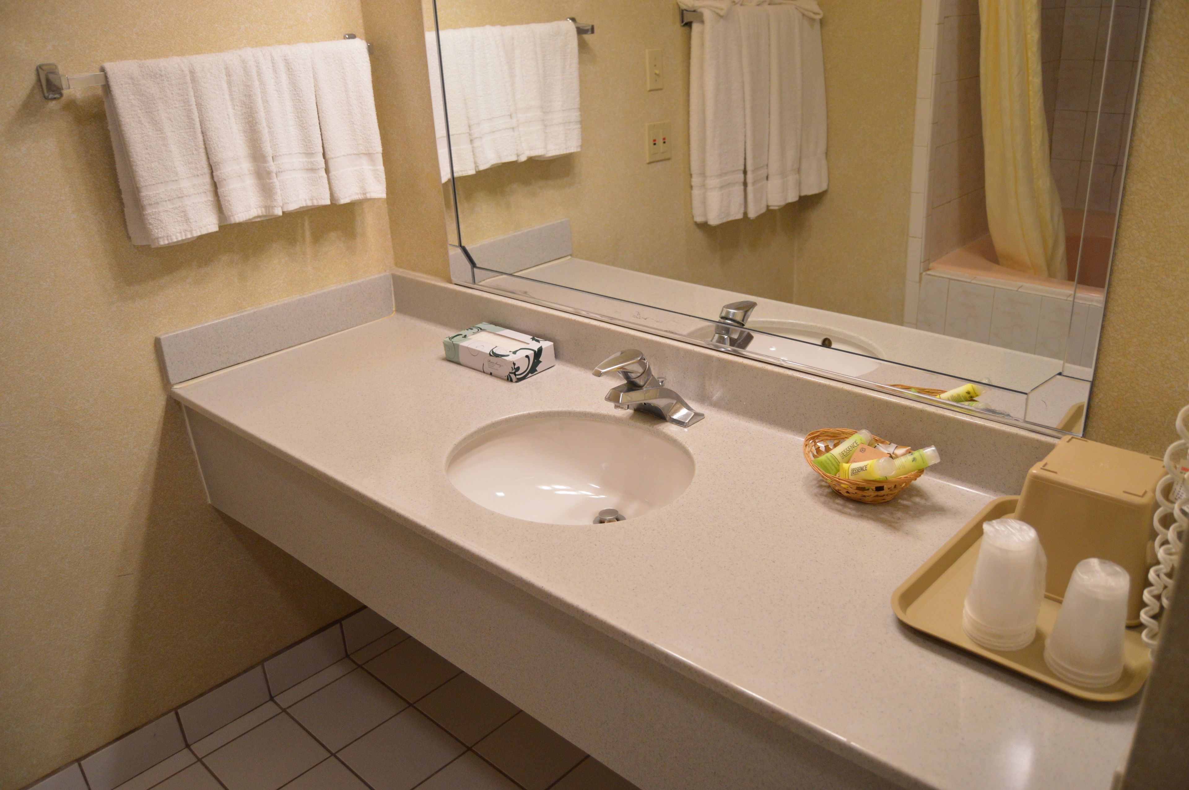 Un baño con lavamanos, espejo y perchero para toallas.