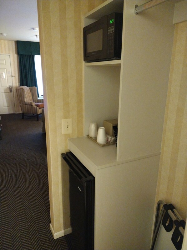 A compact kitchenette with a microwave, a small refrigerator, and a coffee maker on a shelf. - Cedar Lodge (El Portal)