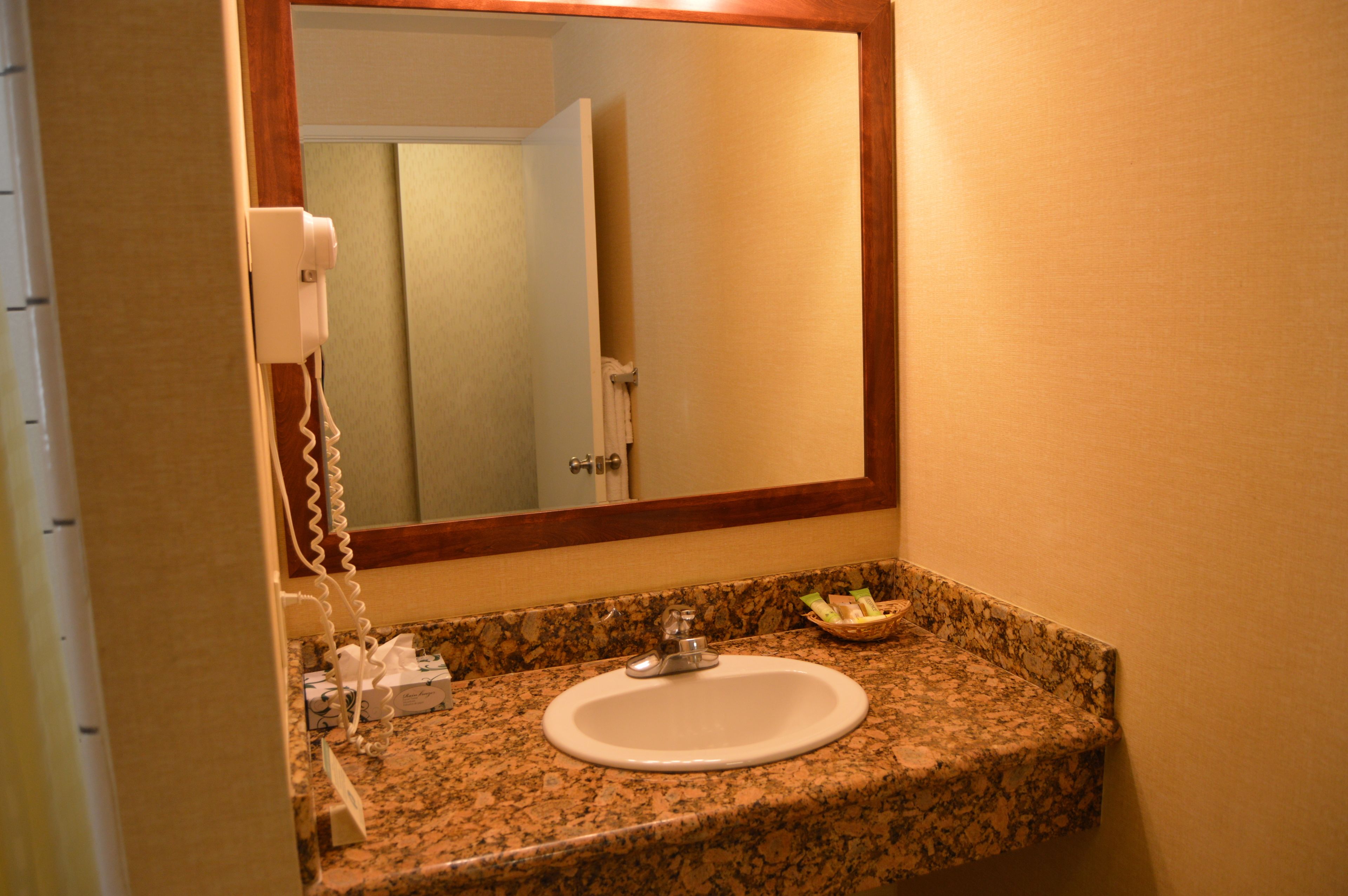 A bathroom with a granite countertop, a white sink, and a mirror.