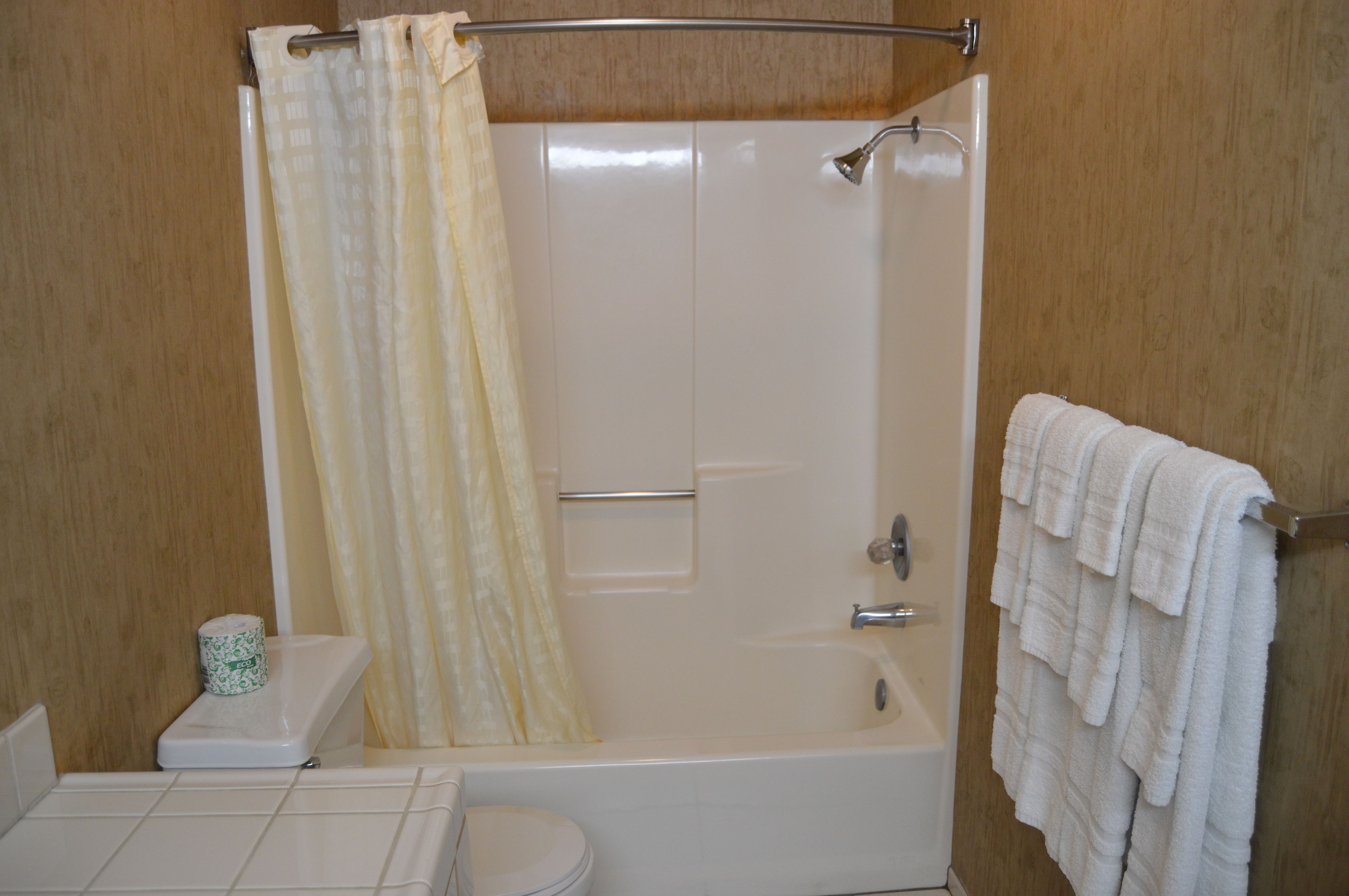 Un baño con ducha, inodoro y toallero.