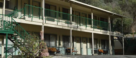 A two-story motel with a covered porch, outdoor seating, and a staircase.