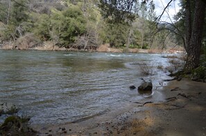 A river with a sandy bank and trees in the background. - Cedar Lodge (El Portal)