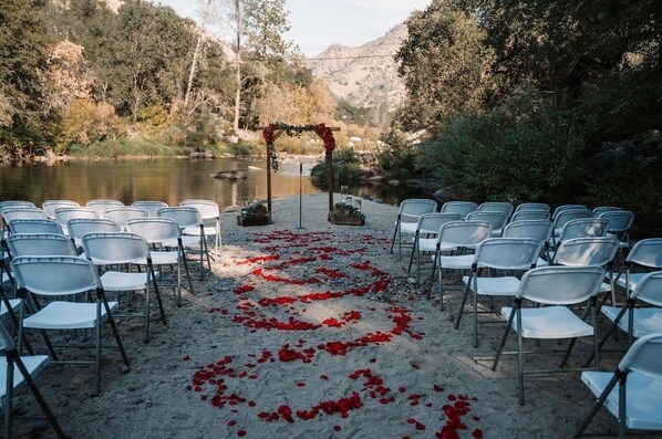 Decoración para una ceremonia frente al mar, con filas de sillas y un arco floral.