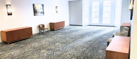 Una habitación amplia con alfombra estampada, un banco de madera, una silla y un armario.