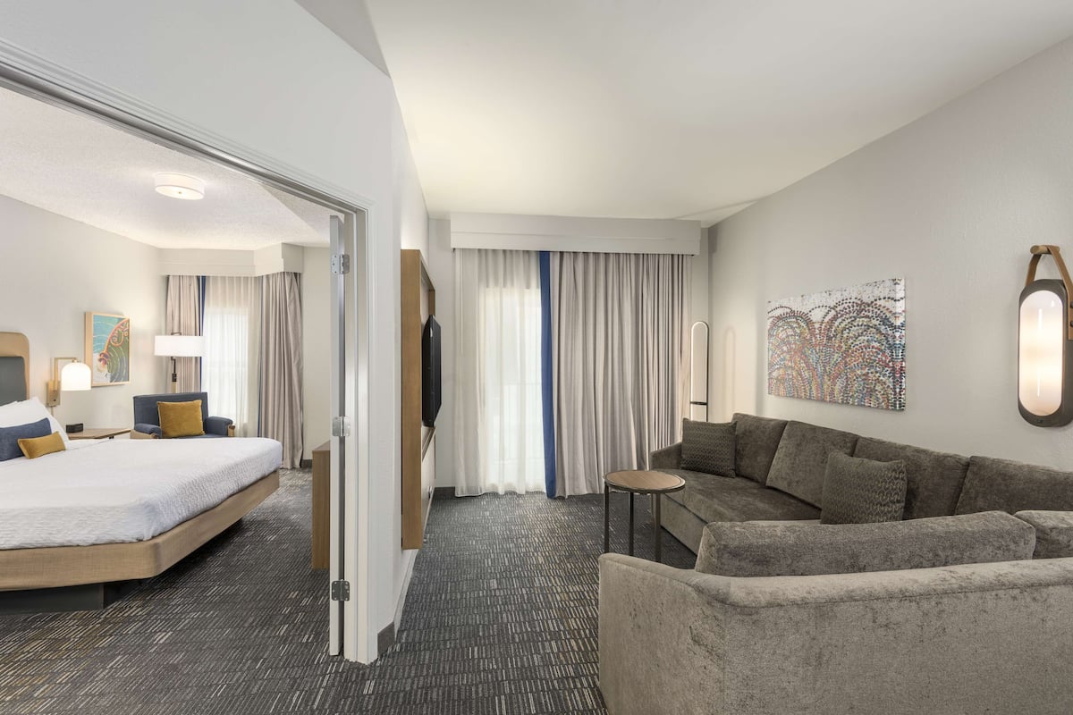 Une chambre d’hôtel avec un lit, un canapé, une petite table et un téléviseur.
