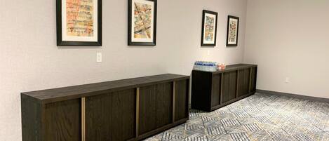 A hallway with a long wooden bench, patterned floor, and framed artwork on the walls.