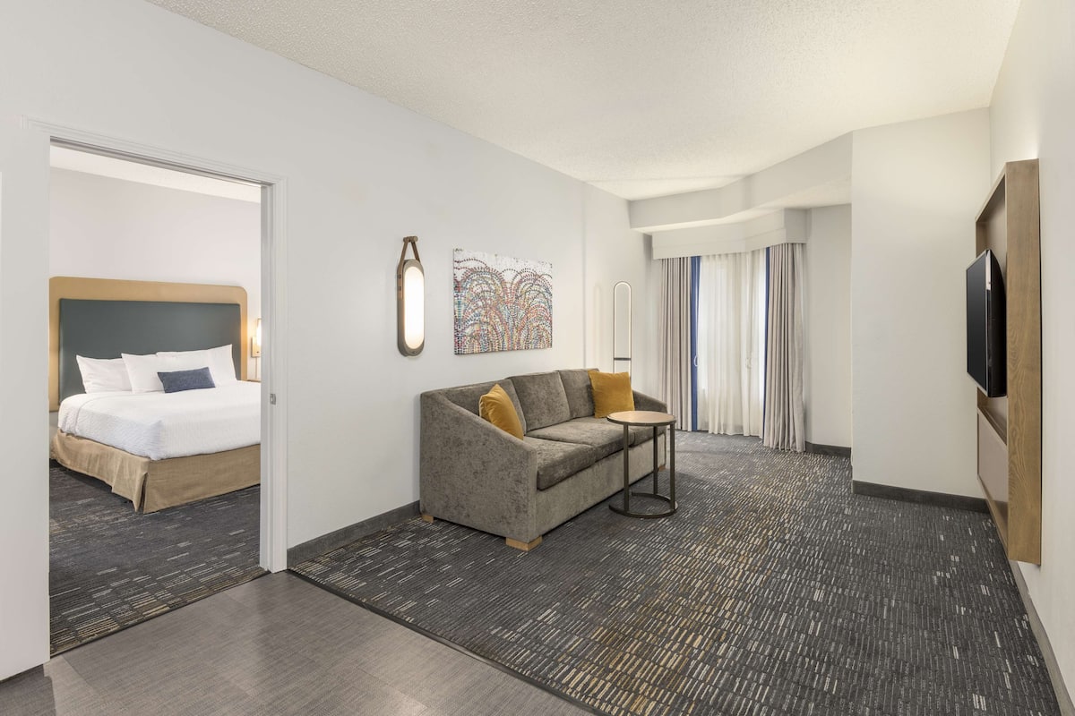 Une chambre d’hôtel avec un lit, un canapé, une petite table et un téléviseur.