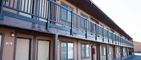Un motel avec une rangée de chambres, chacune dotée d’une porte et d’une fenêtre. Au deuxième étage, un balcon est agrémenté d’une balustrade.