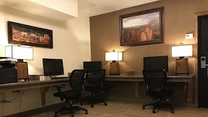 A hotel office with desks, chairs, computers, and two paintings on the wall.