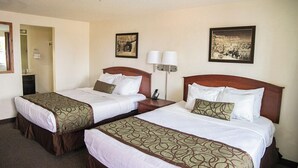 A hotel room with two beds, a bathroom, and a hallway.