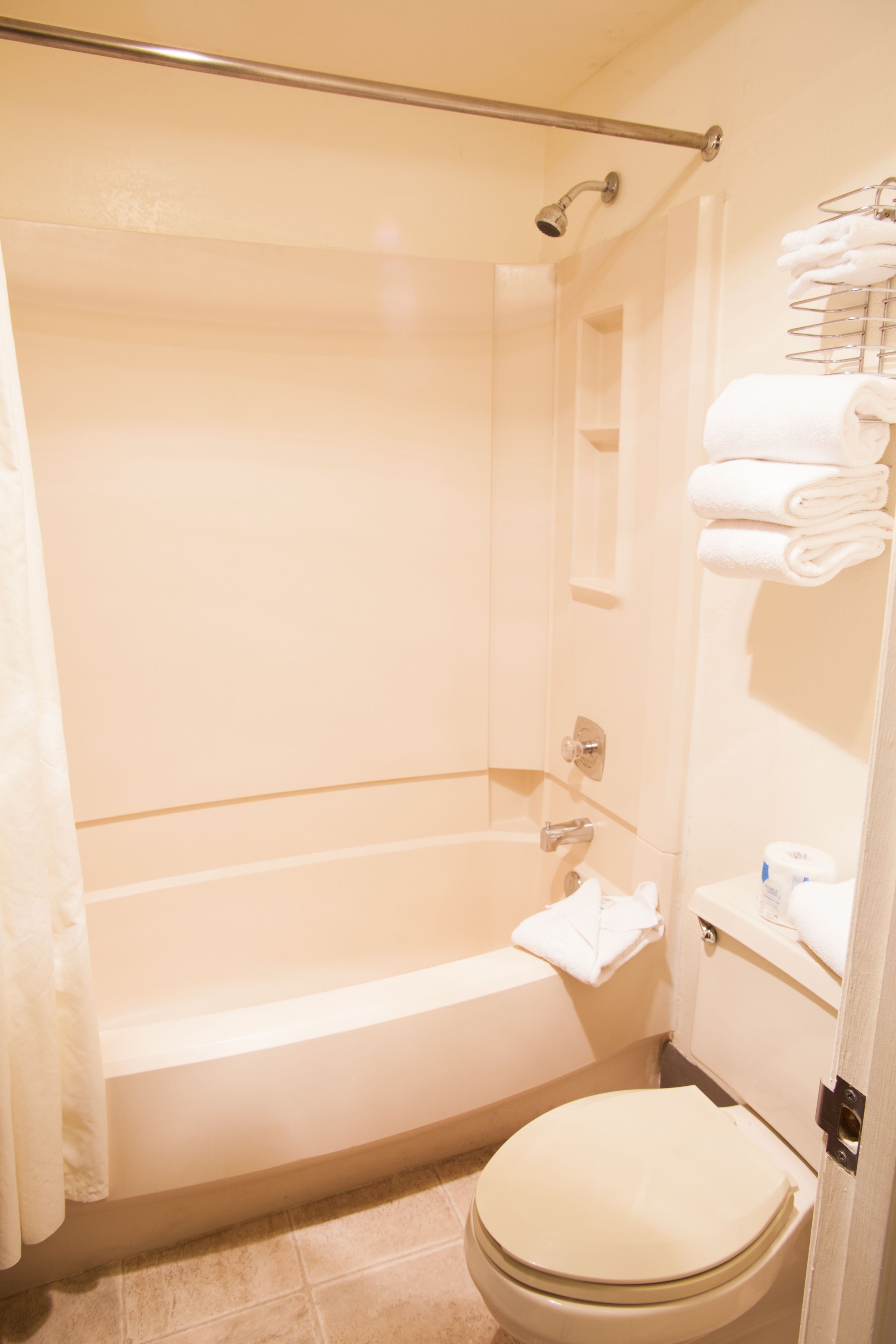 Ein Badezimmer mit Badewanne, Toilette und einem Handtuchhalter mit gefalteten Handtüchern.